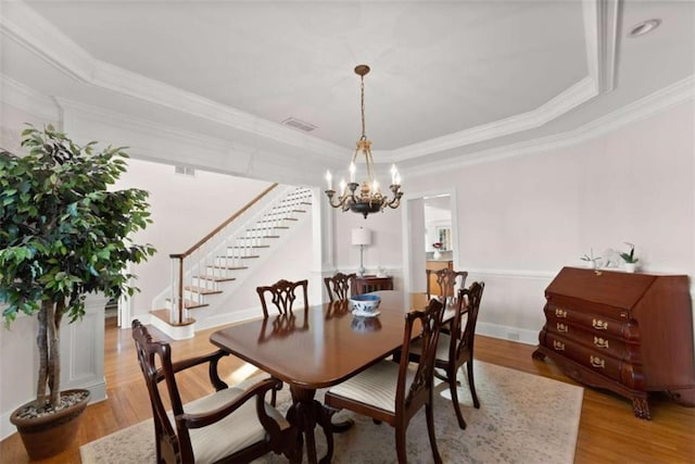 dining space featuring visible vents, stairway, light wood-style flooring, ornamental molding, and a chandelier