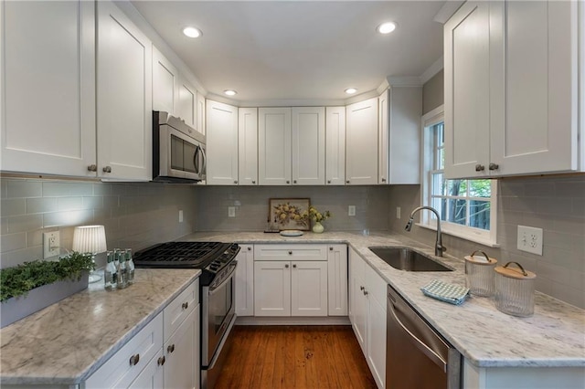 kitchen with stainless steel appliances, a sink, white cabinetry, light stone countertops, and recessed lighting