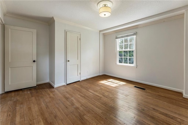 unfurnished bedroom featuring wood finished floors, ornamental molding, baseboards, and a closet