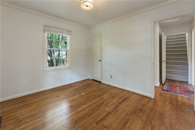 unfurnished bedroom with wood finished floors, crown molding, and baseboards