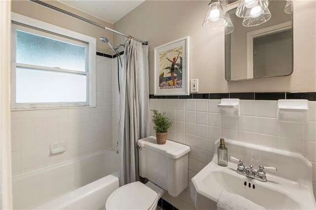 full bath with a sink, toilet, shower / tub combo with curtain, and tile walls