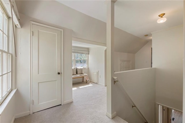 corridor featuring an upstairs landing, light colored carpet, baseboards, and vaulted ceiling