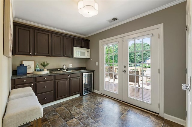 kitchen featuring beverage cooler, white microwave, a sink, baseboards, and dark brown cabinets