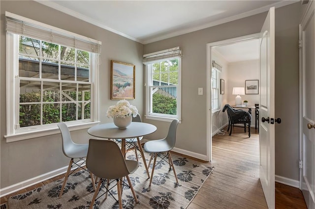 dining space featuring baseboards, wood finished floors, and ornamental molding