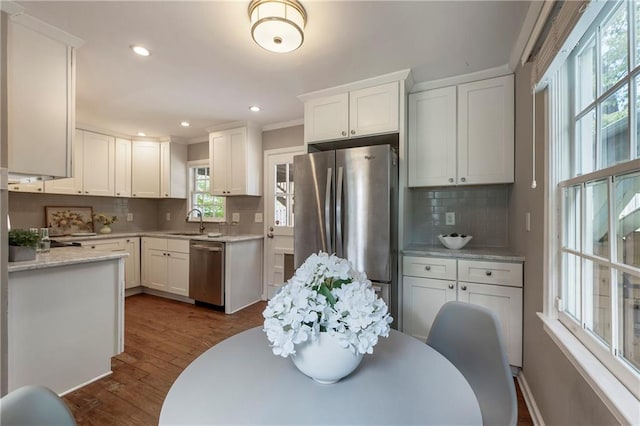 kitchen with stainless steel appliances, a sink, tasteful backsplash, dark wood-style floors, and white cabinetry
