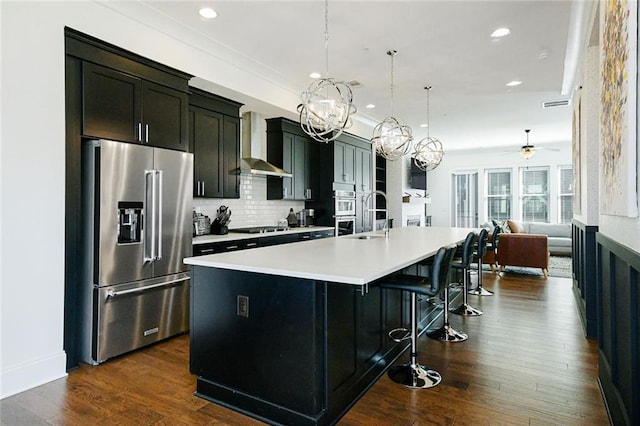 6666 Sterling Dr, Sandy Springs, GA 30328 - kitchen with stainless steel appliances, wall chimney exhaust hood, a large island with sink, light countertops, and a chandelier