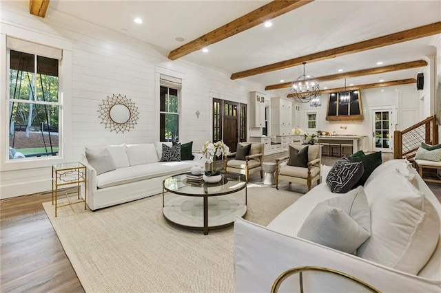 living room featuring light hardwood / wood-style flooring, beam ceiling, and a chandelier