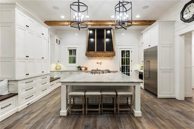 kitchen with stainless steel appliances, decorative light fixtures, beam ceiling, extractor fan, and dark hardwood / wood-style floors