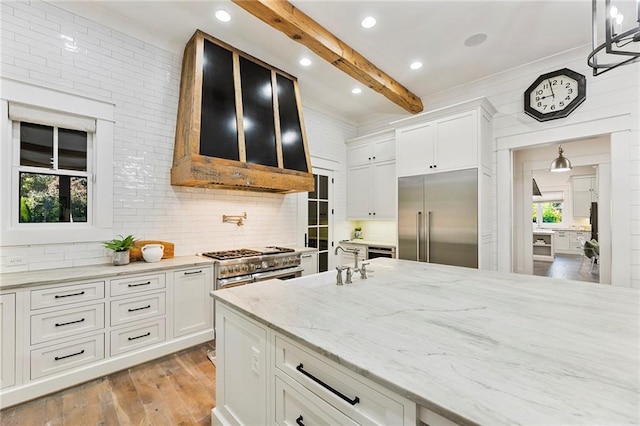 kitchen featuring white cabinetry, high quality appliances, beamed ceiling, and plenty of natural light