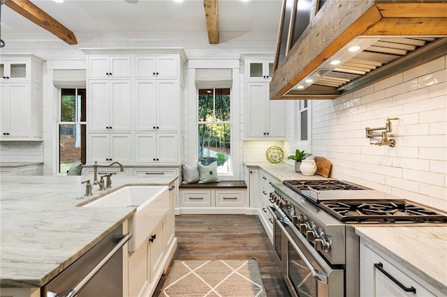 kitchen featuring white cabinets, beam ceiling, light stone countertops, dark wood-type flooring, and stainless steel appliances