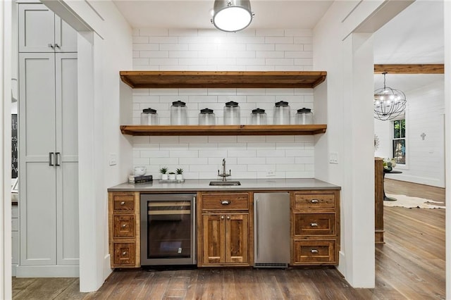 bar featuring dark wood-type flooring, wine cooler, tasteful backsplash, and hanging light fixtures