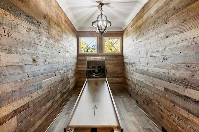 game room featuring wooden walls, a notable chandelier, and dark hardwood / wood-style flooring