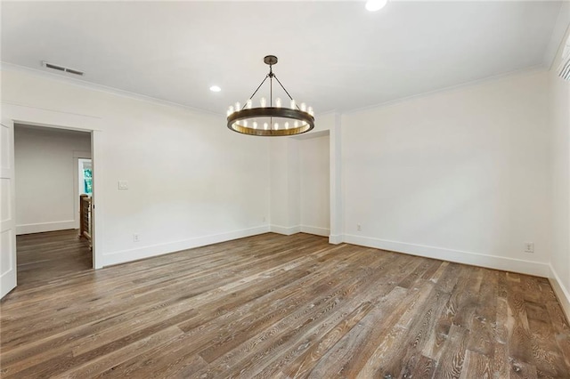 spare room featuring a chandelier, crown molding, and dark hardwood / wood-style flooring