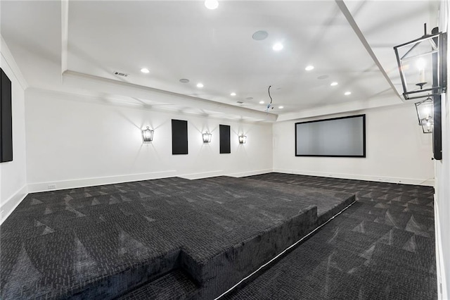 cinema room with ornamental molding and dark colored carpet