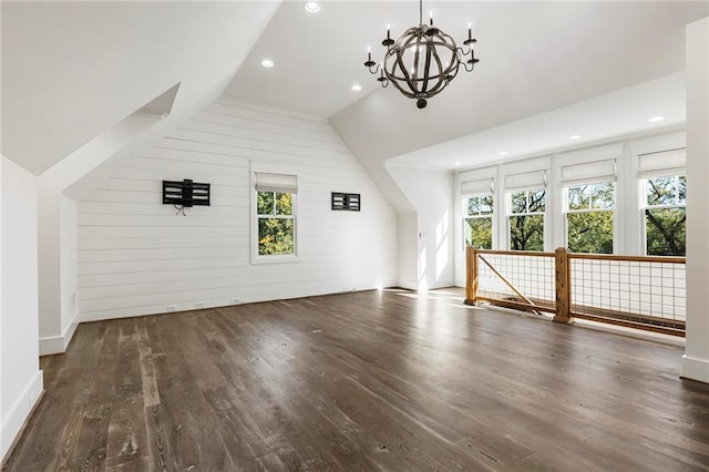 additional living space with dark wood-type flooring, a healthy amount of sunlight, vaulted ceiling, and wooden walls