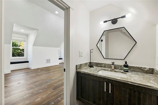 bathroom with vanity, wood-type flooring, and vaulted ceiling