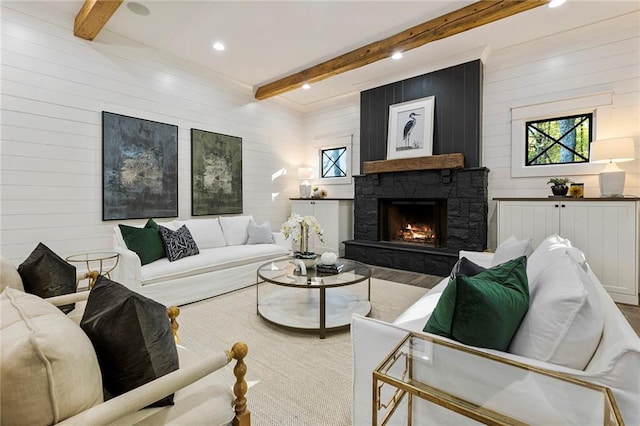 living room with wood walls, beamed ceiling, and a fireplace