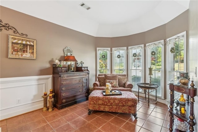 living area featuring tile patterned flooring, a wainscoted wall, a healthy amount of sunlight, and visible vents