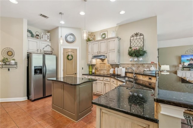 kitchen with a sink, decorative backsplash, under cabinet range hood, stainless steel refrigerator with ice dispenser, and visible vents