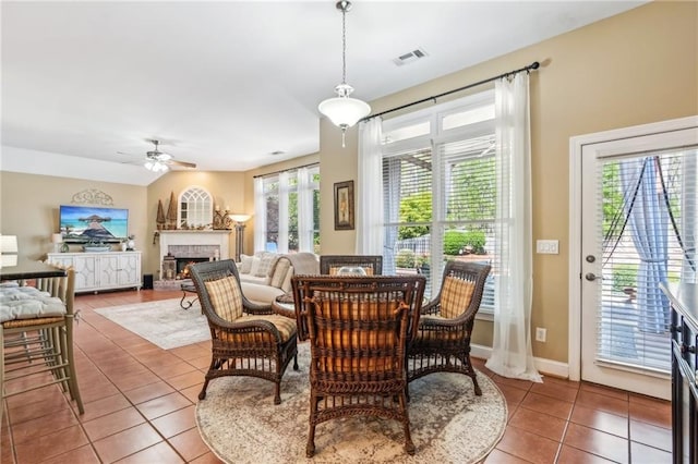dining area with ceiling fan, visible vents, tile patterned flooring, a brick fireplace, and baseboards