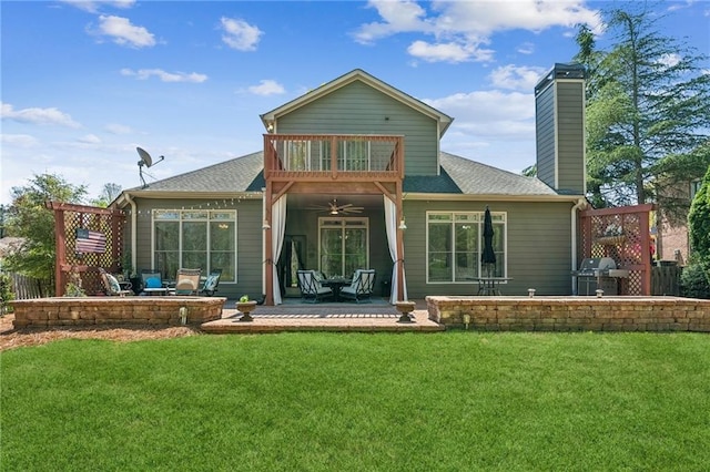 rear view of property with a lawn, ceiling fan, a chimney, and a patio
