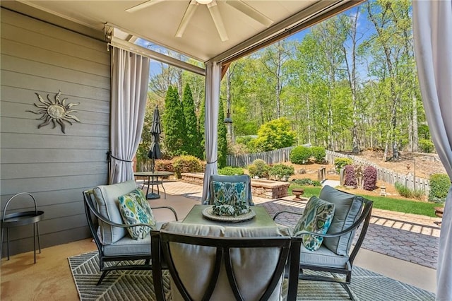 view of patio with fence, a ceiling fan, and outdoor dining space