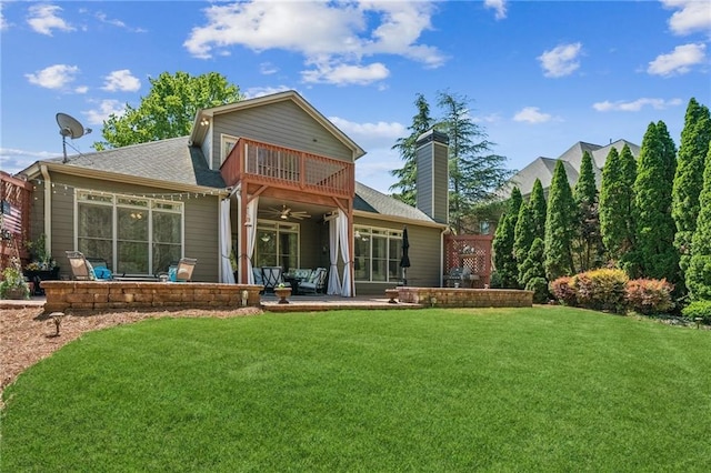 back of property featuring ceiling fan, a balcony, roof with shingles, a patio area, and a yard
