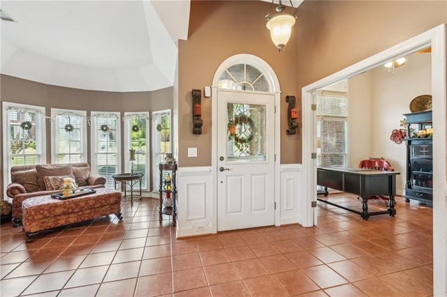 entrance foyer with a high ceiling, light tile patterned floors, and a wainscoted wall