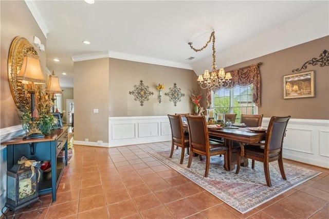 tiled dining area with crown molding, wainscoting, a decorative wall, recessed lighting, and a chandelier