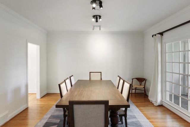 dining area with crown molding, light wood-style flooring, and baseboards