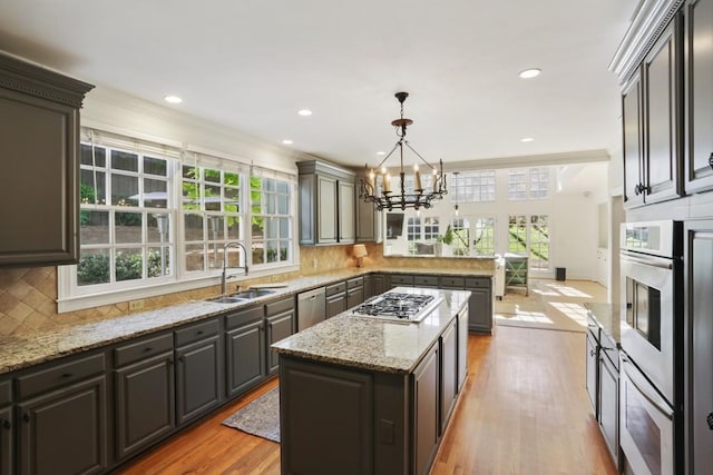 kitchen featuring light wood-type flooring, appliances with stainless steel finishes, a peninsula, plenty of natural light, and a sink