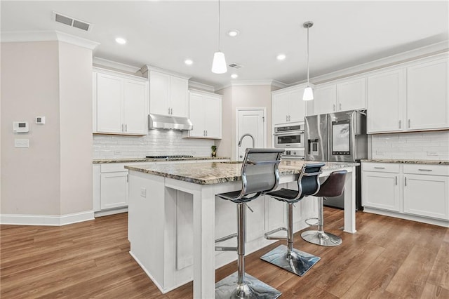 4110 Morgan Elizabeth Way, Cumming, GA 30041 - kitchen featuring appliances with stainless steel finishes, under cabinet range hood, ornamental molding, a breakfast bar, and decorative backsplash