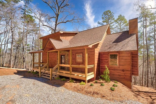 exterior space featuring a chimney, a shingled roof, and covered porch