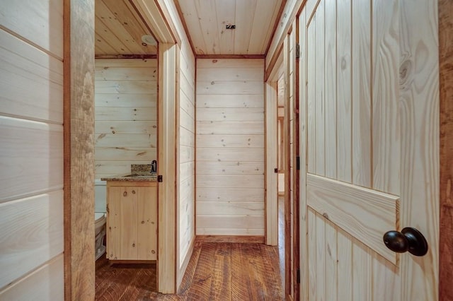 hallway with wooden walls, wooden ceiling, and dark wood-style flooring