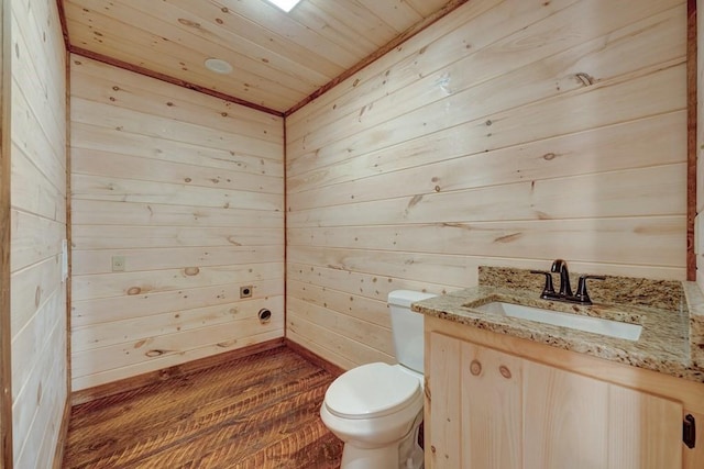 half bathroom featuring vanity, toilet, wood ceiling, wood finished floors, and wooden walls
