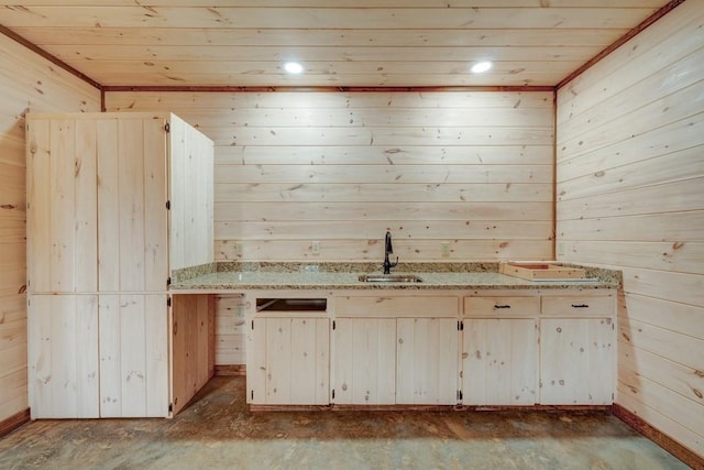 kitchen with wooden ceiling, wooden walls, a sink, and light stone countertops