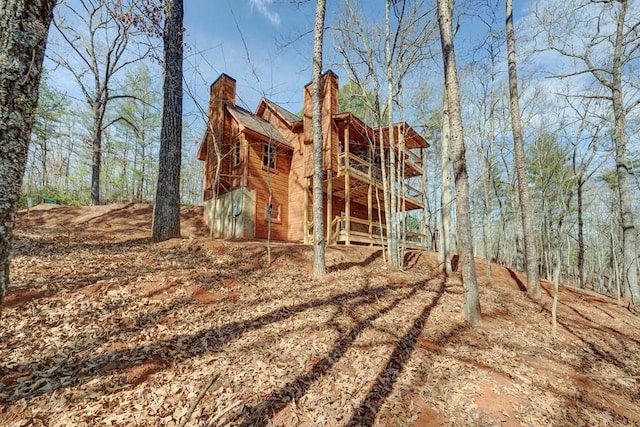 view of front of house featuring a chimney and a forest view