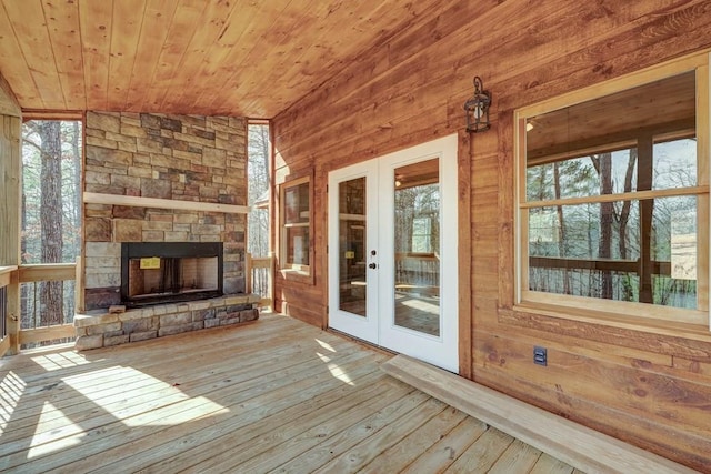 wooden terrace featuring french doors and an outdoor stone fireplace