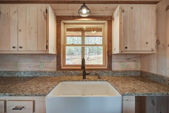 kitchen featuring light brown cabinets, stone counters, and a sink