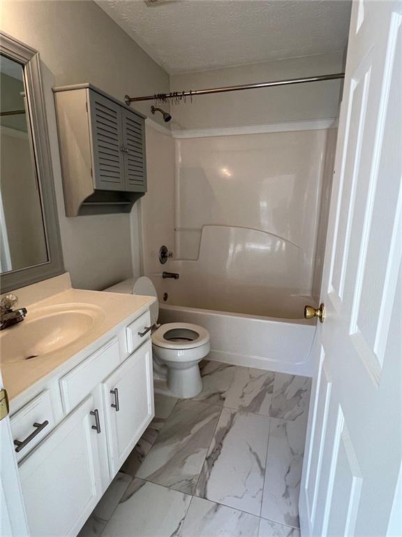 full bathroom featuring a textured ceiling, toilet, vanity, and shower / bathing tub combination