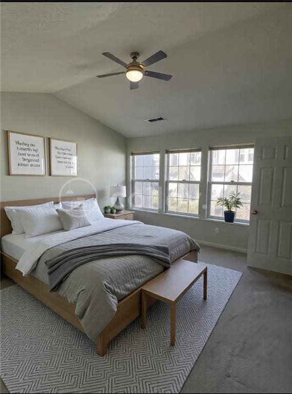 carpeted bedroom with ceiling fan and vaulted ceiling