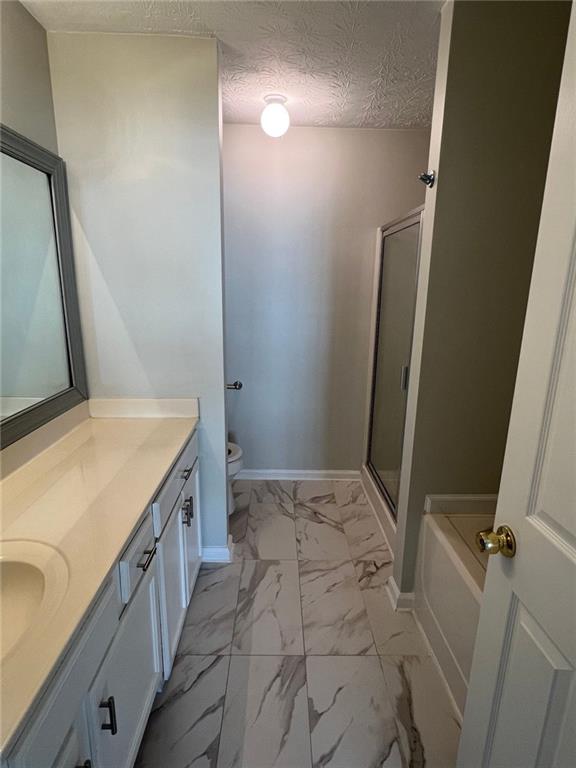 full bathroom featuring a textured ceiling, independent shower and bath, toilet, and vanity