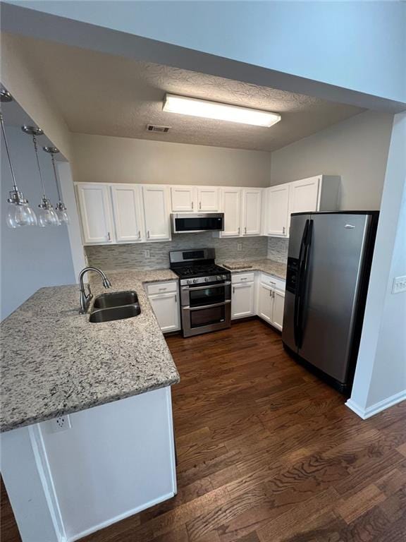 kitchen with stainless steel appliances, sink, white cabinets, and decorative light fixtures