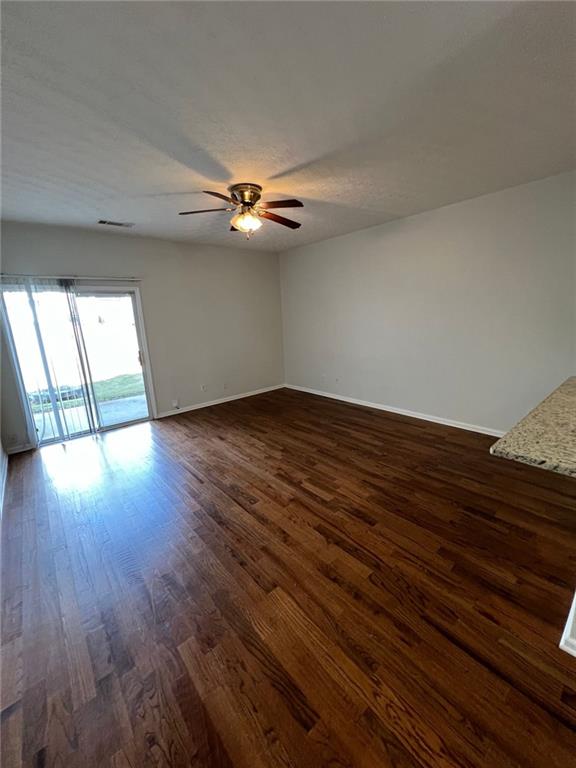 empty room with ceiling fan and dark hardwood / wood-style floors