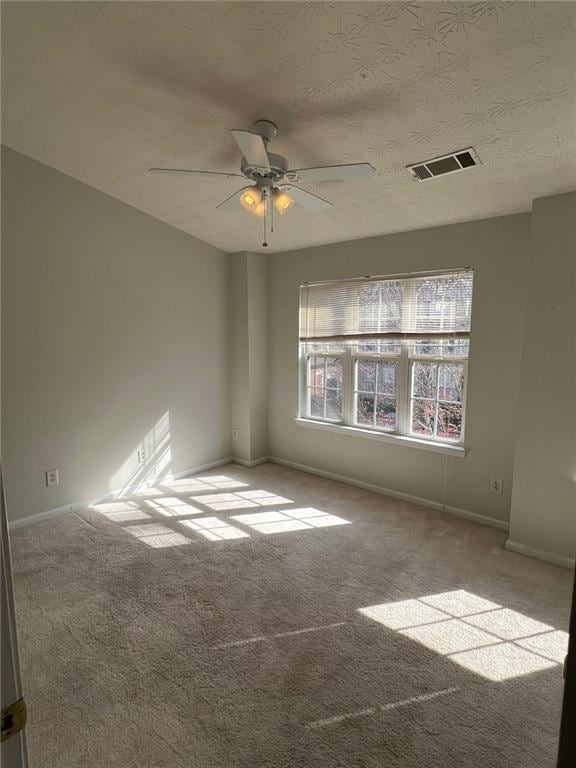 carpeted spare room featuring ceiling fan and a textured ceiling