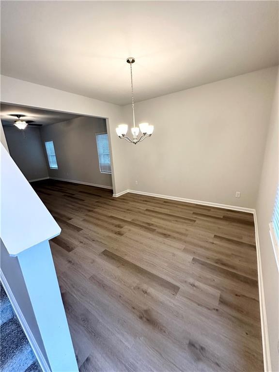 836 Courthouse Park Dr, Temple, GA 30179 - unfurnished dining area with a chandelier, dark wood-style floors, and baseboards