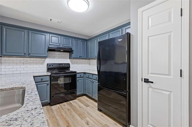 2183 Miranda Dr, Morrow, GA 30260 - kitchen with black appliances, blue cabinetry, under cabinet range hood, light wood finished floors, and backsplash