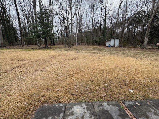 view of yard featuring a storage unit, a wooded view, and an outdoor structure