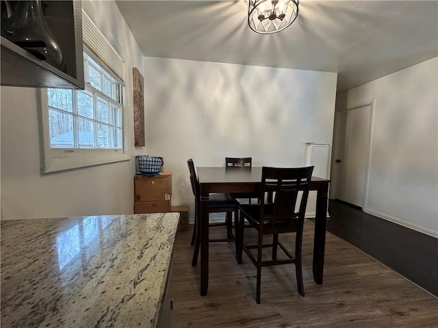 dining area with an inviting chandelier and dark wood finished floors