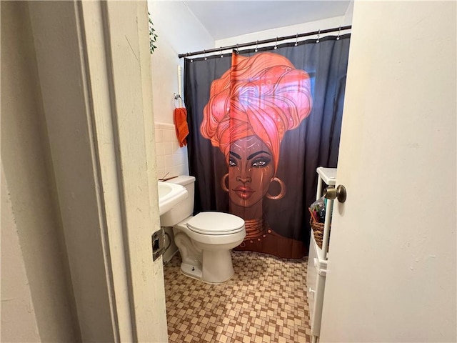 full bathroom featuring tile patterned floors, toilet, and tile walls